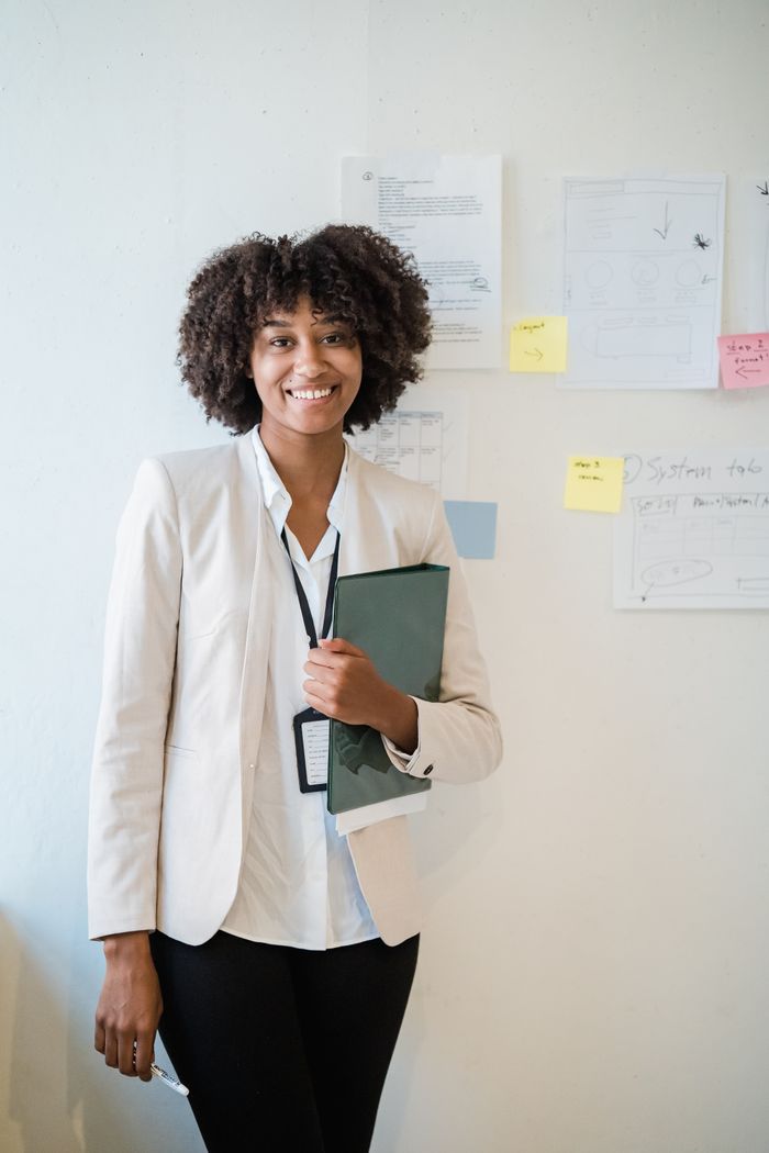 Entreprise Smiling businesswoman in a white office setting, holding documents and exuding confidence.