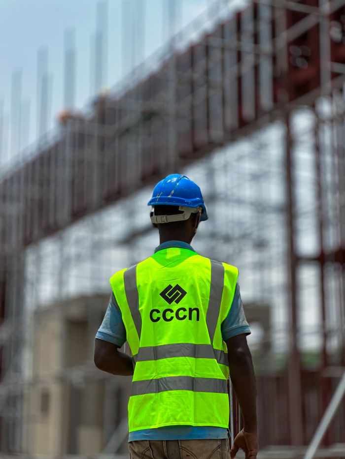 Services A construction worker in a neon vest and hard hat on a building site, emphasizing safety.