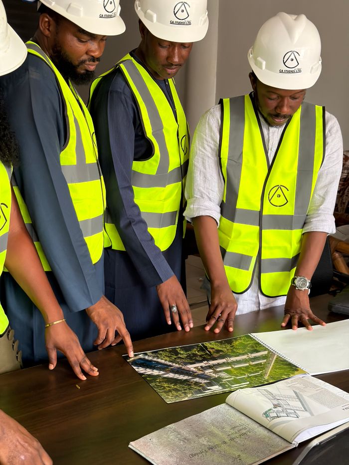 Accueil Group of engineers and architects examine building plans with safety gear.