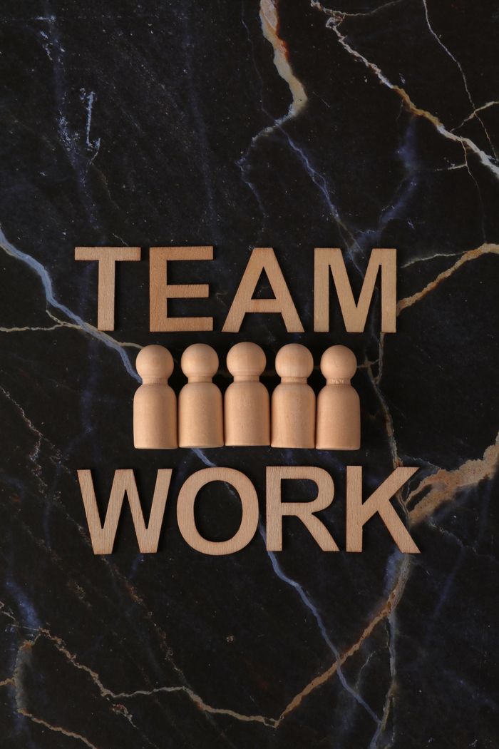 Services Top view of wooden figures and 'TEAM WORK' letters on marble background symbolizing collaboration.