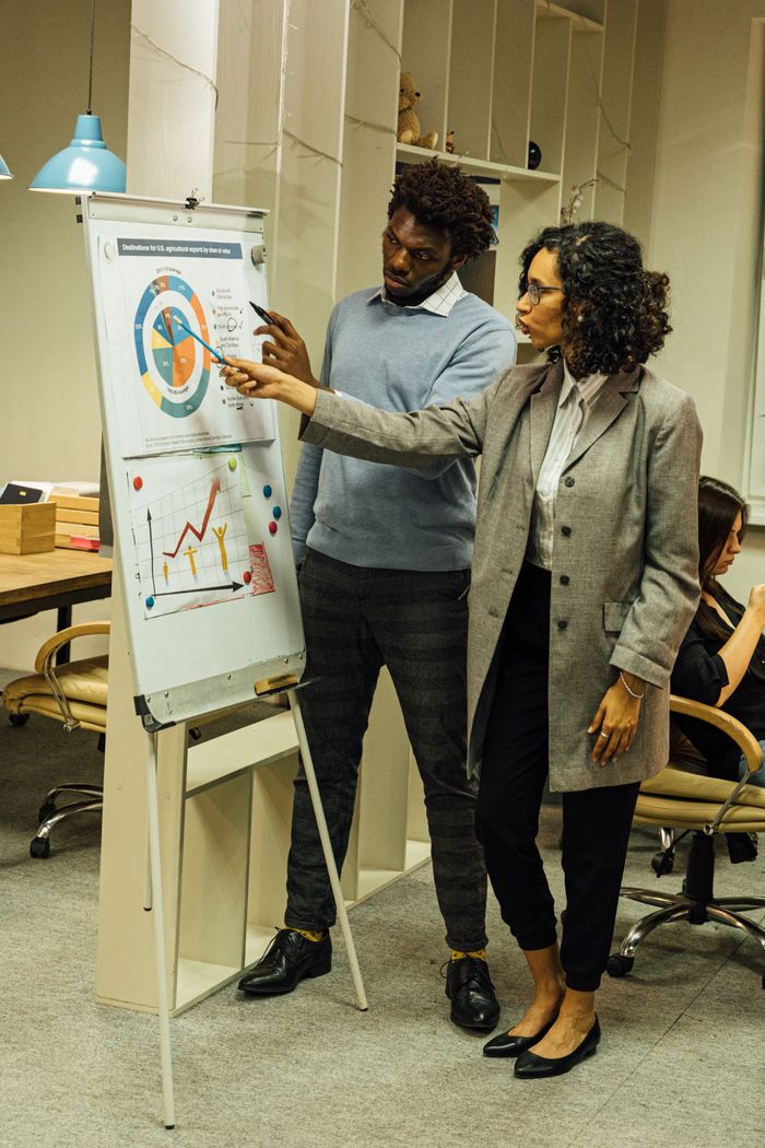 Accueil Colleagues engage in data analysis discussion during a team meeting in a contemporary office space.