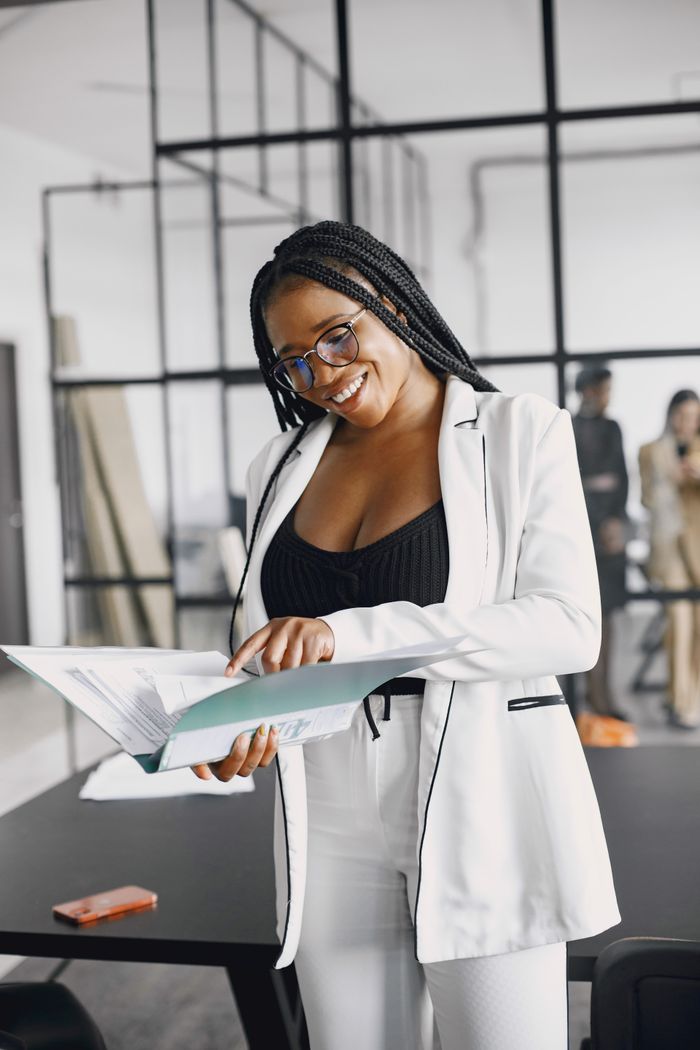 Services Professional woman in a white blazer reviewing documents in a modern office setting.