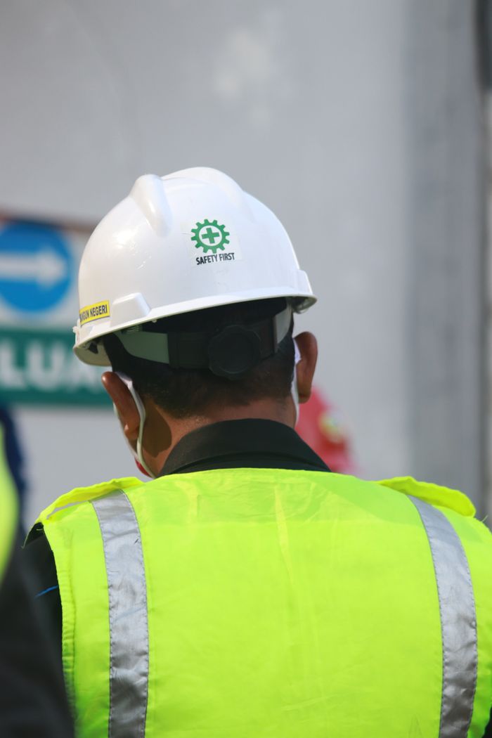Services Worker with safety vest and helmet at a construction site in Central Java, Indonesia.